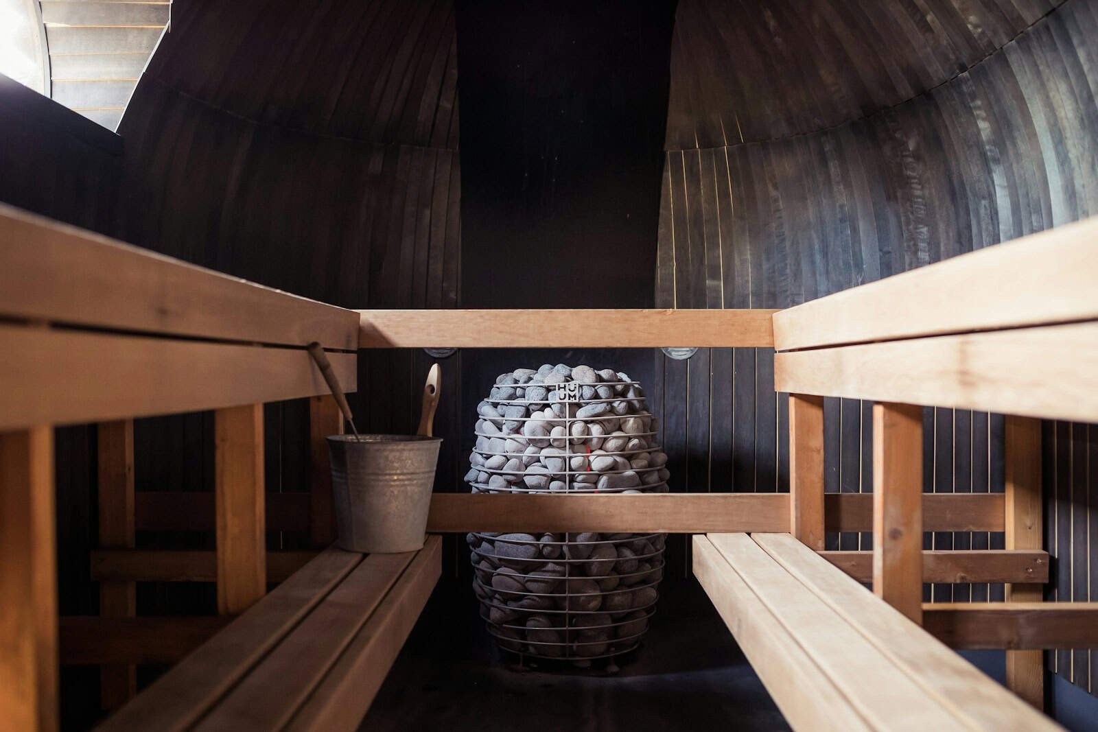 Holzverkleidter Innenraum einer Biosauna mit Holzbänken und warmem Licht