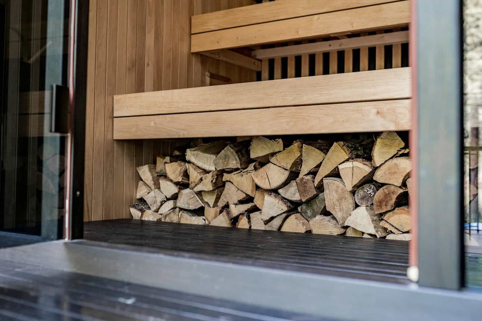 Holzbank in einer Kräutersauna mit frischen Kräuterbündeln auf den Saunasteinen