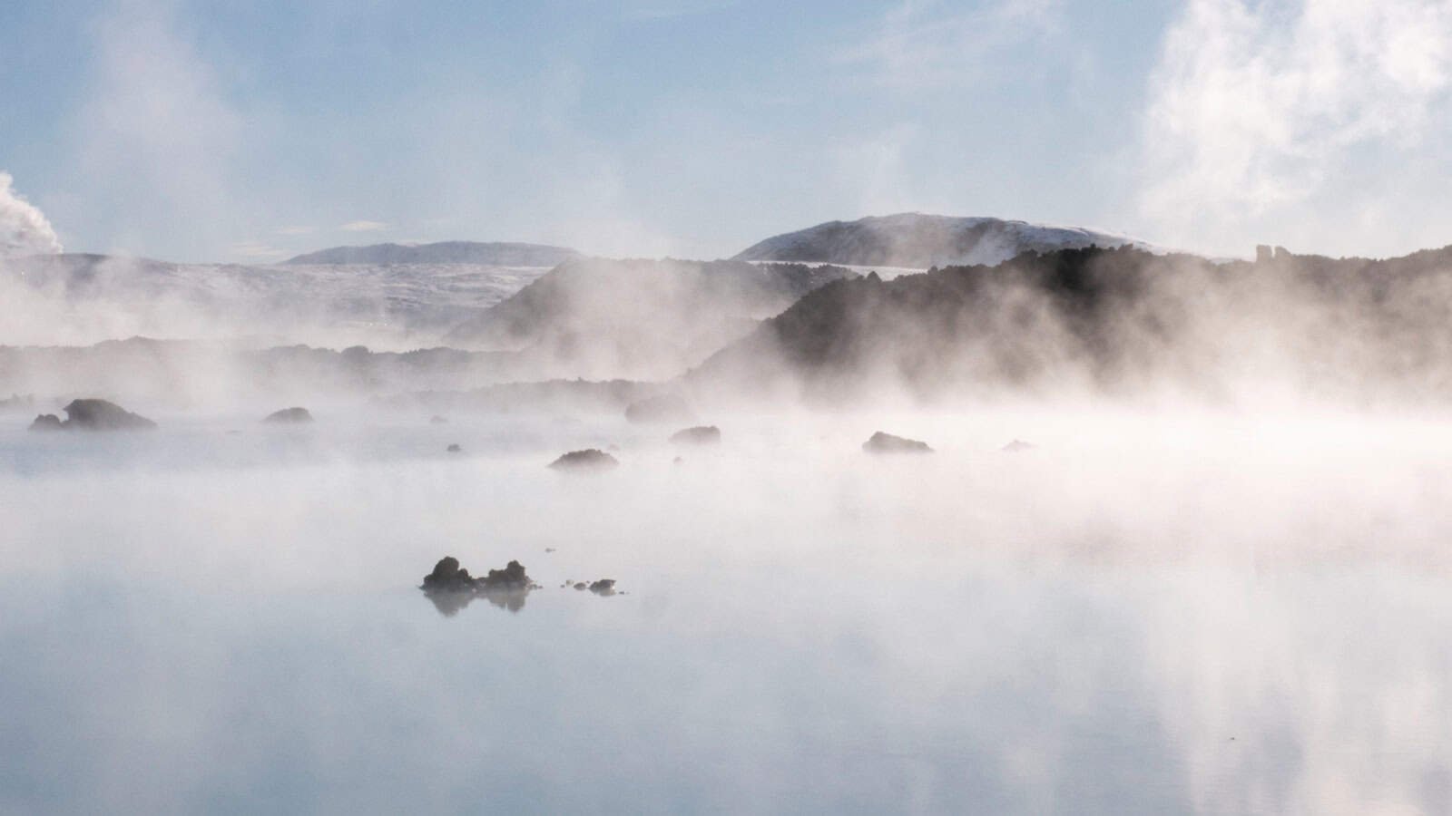 Dampfendes Außenbecken eines japanischen Onsen zwischen schneebedeckten Felsen